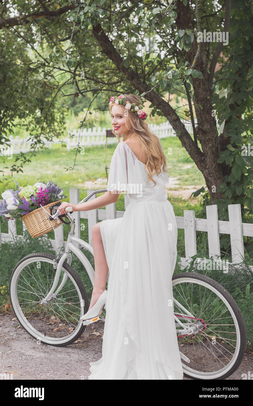 Beautiful smiling young bride en robe de mariage riding bicycle Banque D'Images