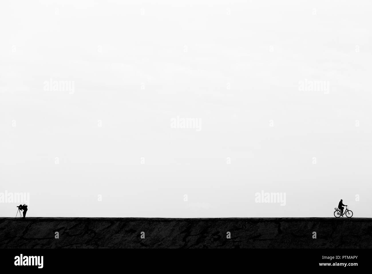 Paysage noir et blanc minimal avec un photographe et un cycliste Banque D'Images