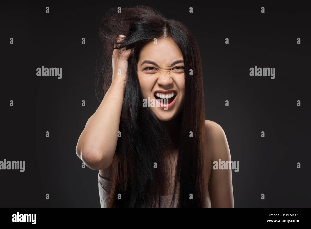 Portrait de femme asiatique émotionnelle avec des cheveux sains isolated on black Banque D'Images