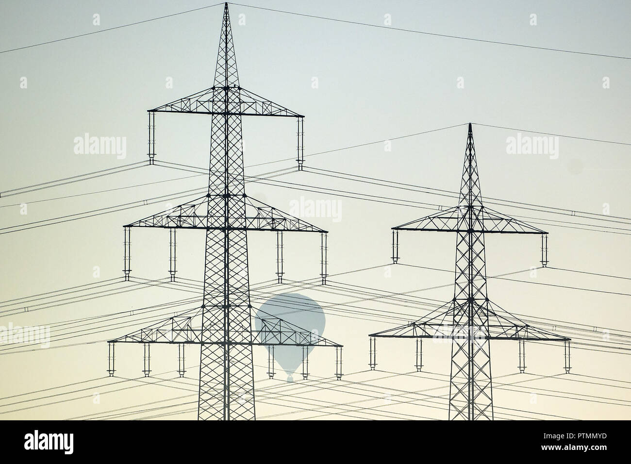 10 octobre 2018, en Rhénanie du Nord-Westphalie, Roggendorf : un ballon à air chaud passe sur des poteaux électriques dans le brouillard du matin. Photo : Federico Gambarini/dpa Banque D'Images