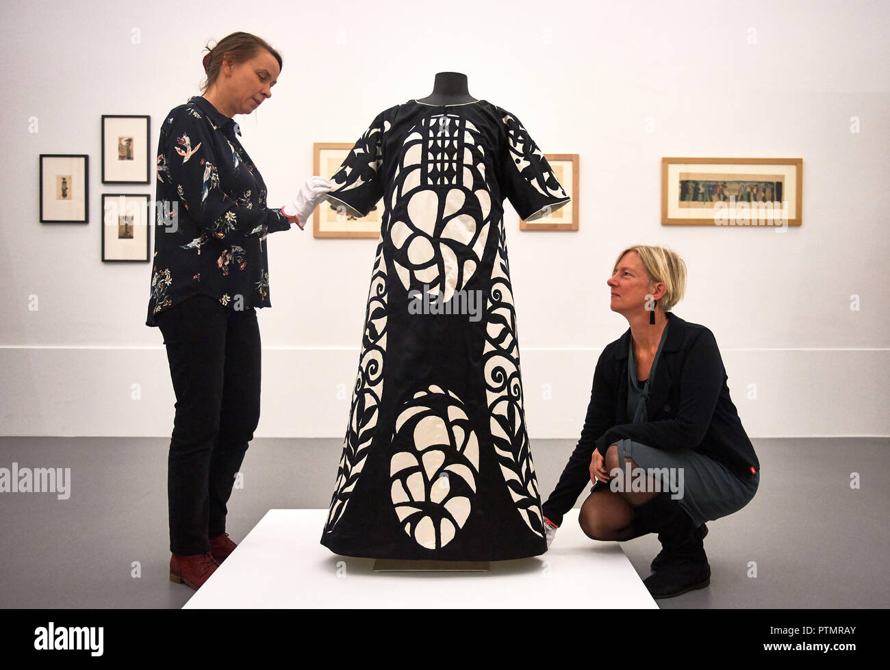 10 octobre 2018, en Rhénanie du Nord-Westphalie, Krefeld : Les conservateurs Magdalena Holzhey (l) et l'Ina Ewers-Schultz mettre la touche finale à Josef Hoffmann's 'Ladies' robe pour une redoute'. Dans son exposition 'adaptés à la liberté. La robe de l'artiste autour de 1900 dans la mode, l'Art et société", autour de 300 œuvres de la réforme entre 1900 et 1914. Le spectacle dure du 12 octobre au 24 février 2019. Photo : Bernd Thissen/dpa Banque D'Images