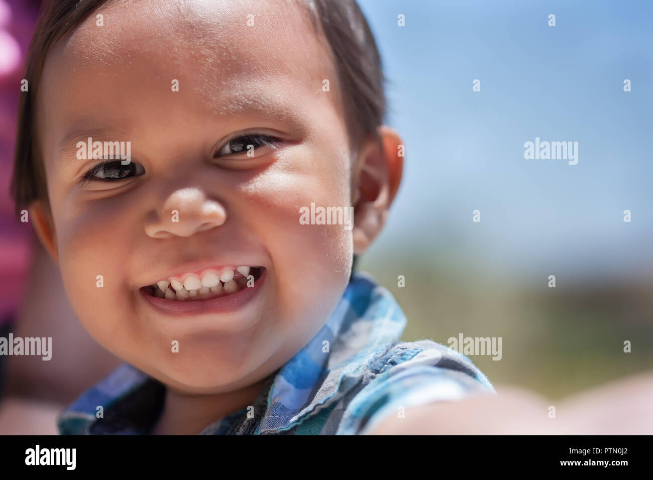 Beau jeune garçon avec un grand sourire et un ensemble complet de dents de bébé à l'extérieur en été excité Banque D'Images
