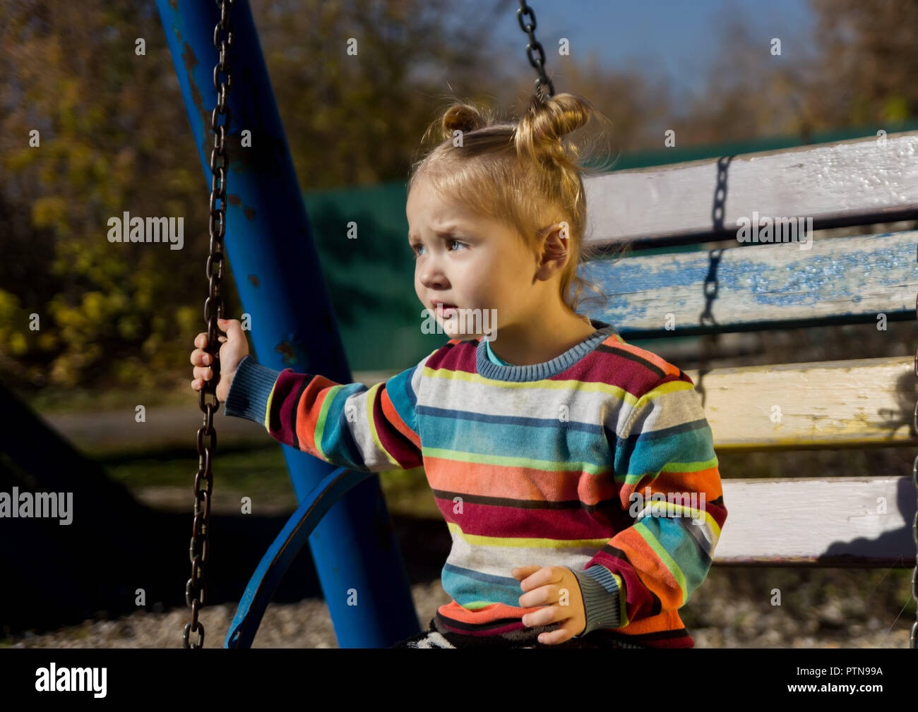 Peu triste fille sur une balançoire dans le parc. Banque D'Images