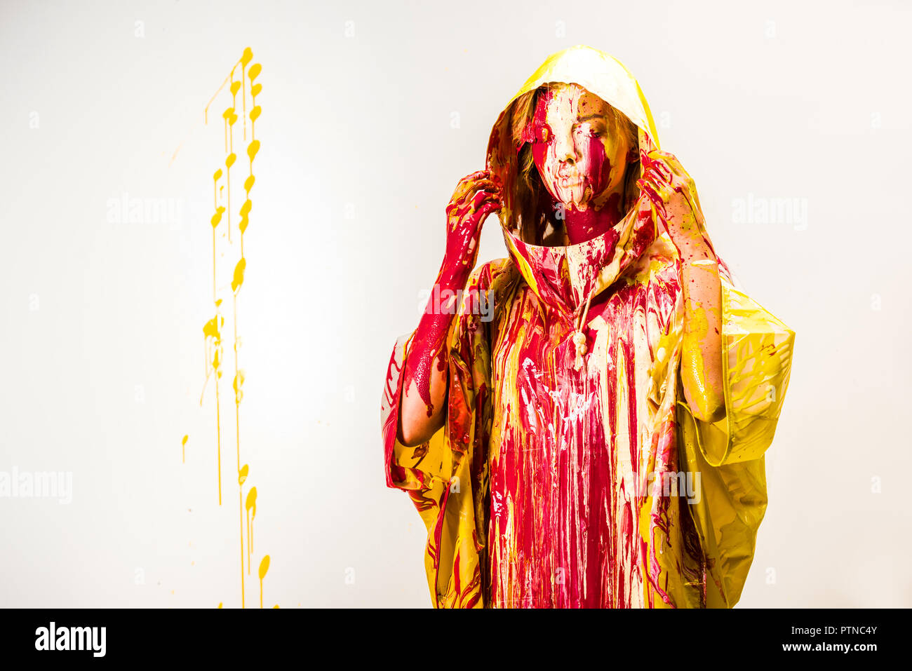 Belle femme en imperméable peint avec les peintures jaune et rouge portant des bois isolated on white Banque D'Images