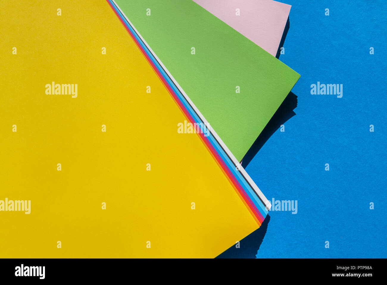 Feuilles de documents dynamiques colorés sur fond bleu Vue de dessus - palette de couleurs Banque D'Images