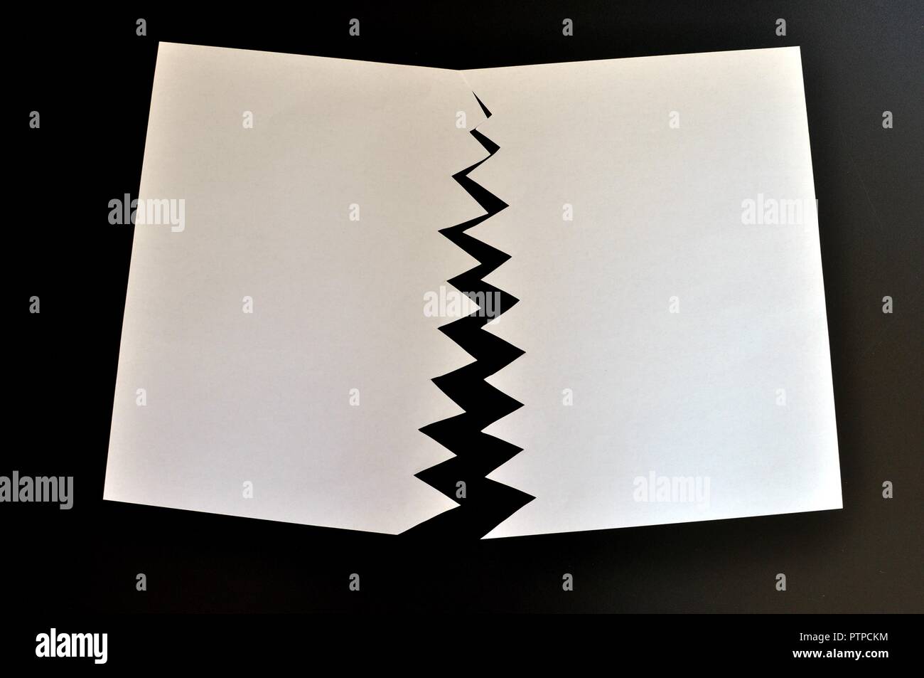 Concept de divisé ou séparé en deux feuilles de papier déchiré. Papier blanc déchiré dans la moitié isolé sur fond noir. Vue d'en haut Banque D'Images