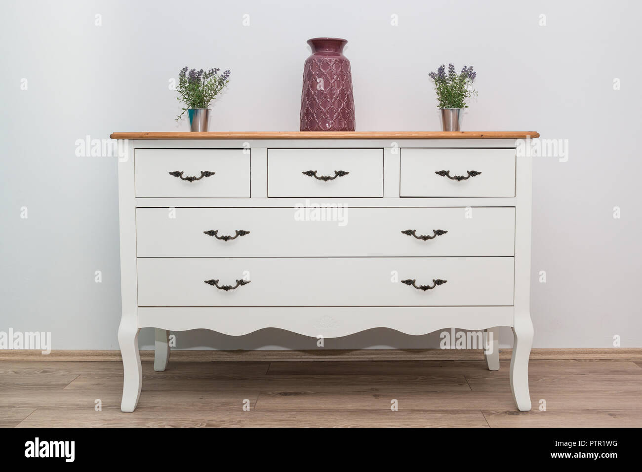 Commode en bois blanc avec trois vases et fleurs sur le mur blanc arrière-plan. Commode close up. Banque D'Images