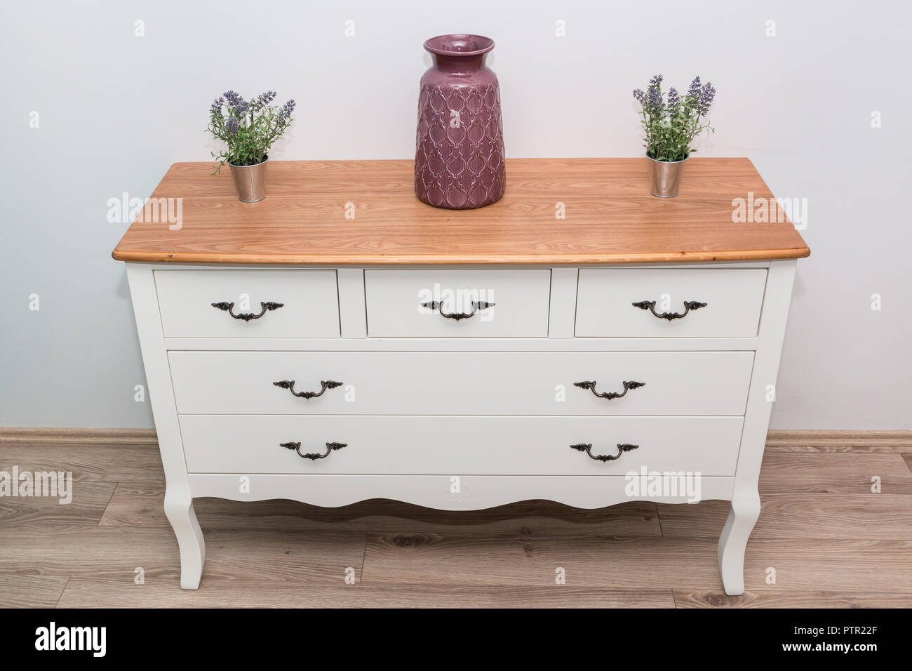 Commode en bois blanc avec trois vases et fleurs sur le mur blanc arrière-plan. Commode close up. Banque D'Images