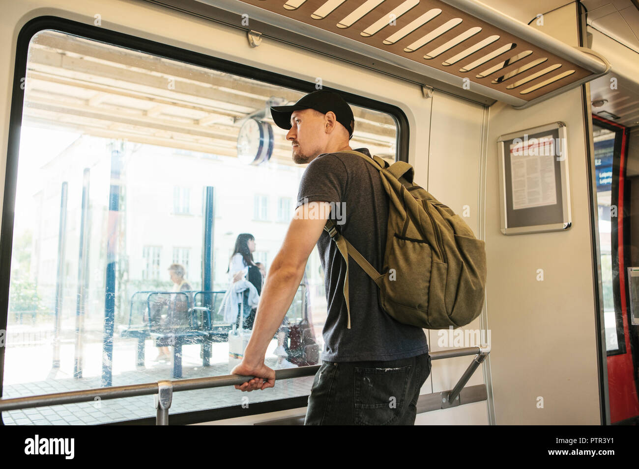 Un jeune mec avec un sac à dos à l'intérieur du train regarde par la  fenêtre à la gare Photo Stock - Alamy