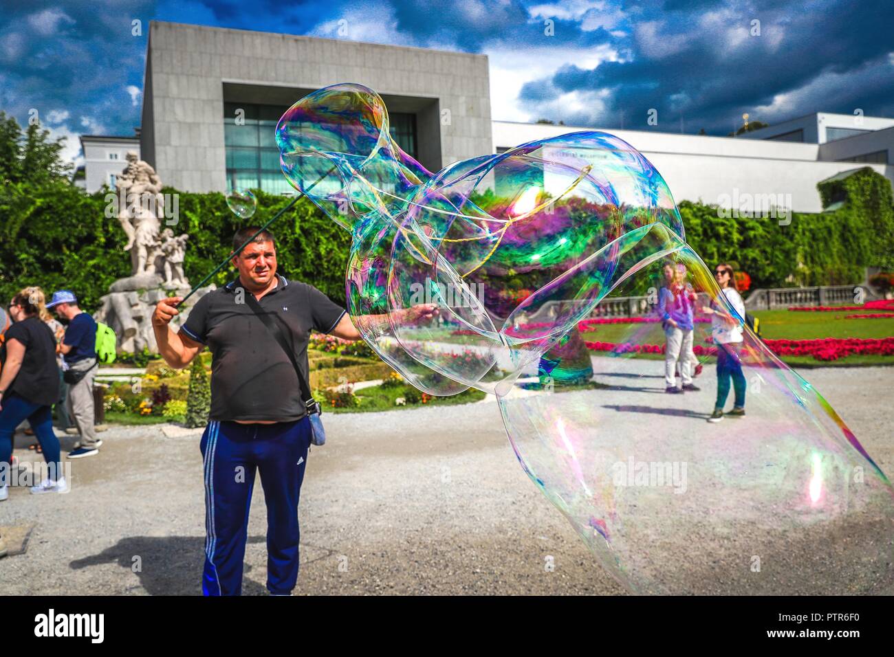 Une bulle de savon maker se produit devant un immeuble moderne de l'Universität Mozarteum (Mozart Université de musique et art dramatique) dans les jardins Mirabell, Banque D'Images