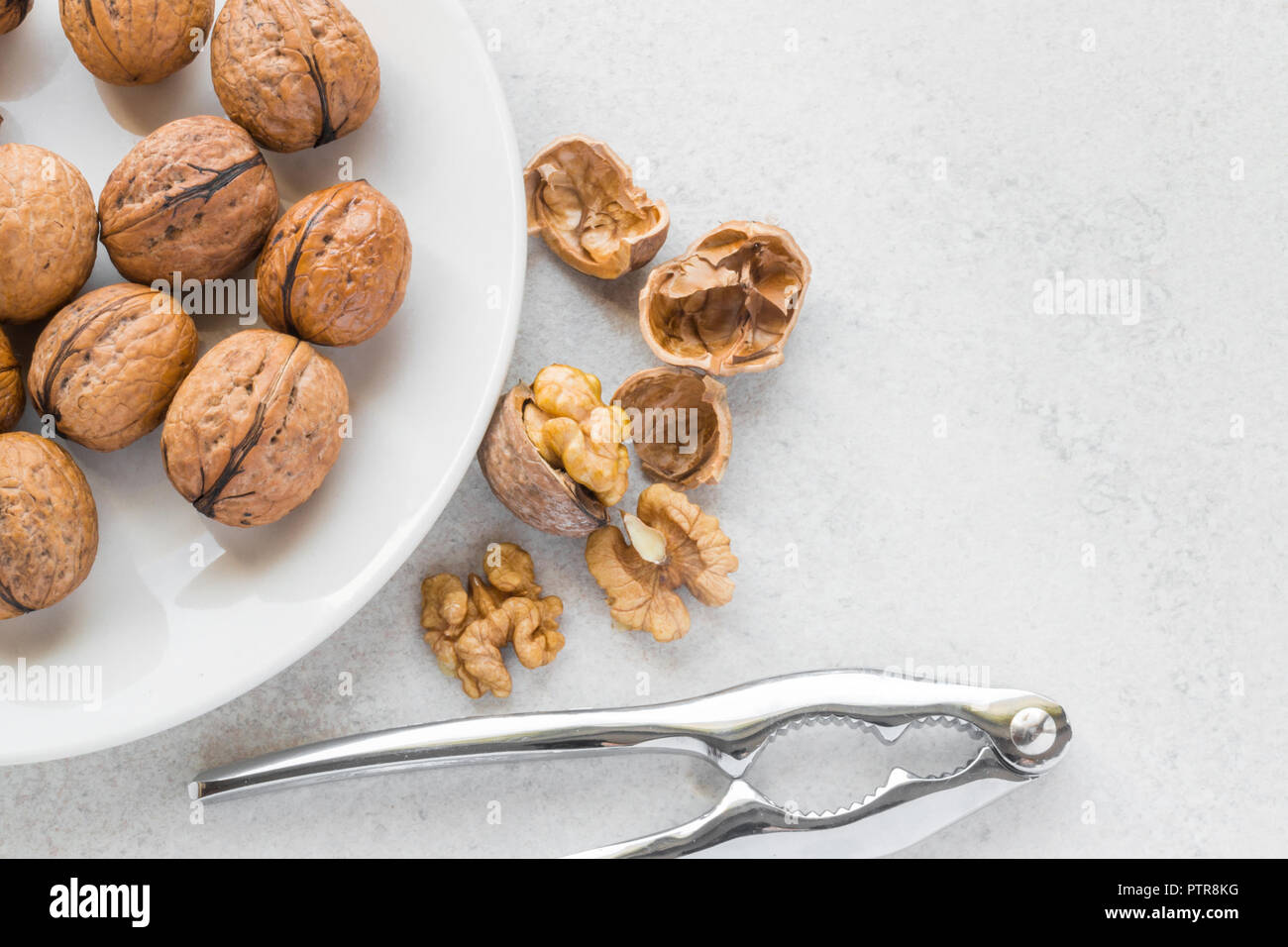 Ensemble les noix sur une plaque de métal blanc, Casse-Noisette et fissuré les noix à côté de Banque D'Images