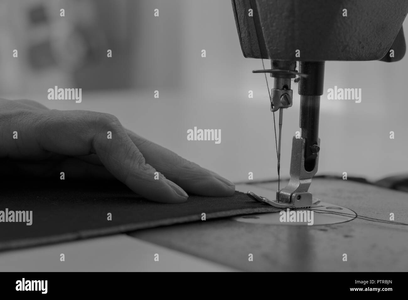 Femme travaillant sur une machine à coudre en noir et blanc Banque D'Images Femme travaillant sur une machine à coudre en noir et blanc Banque D'Images