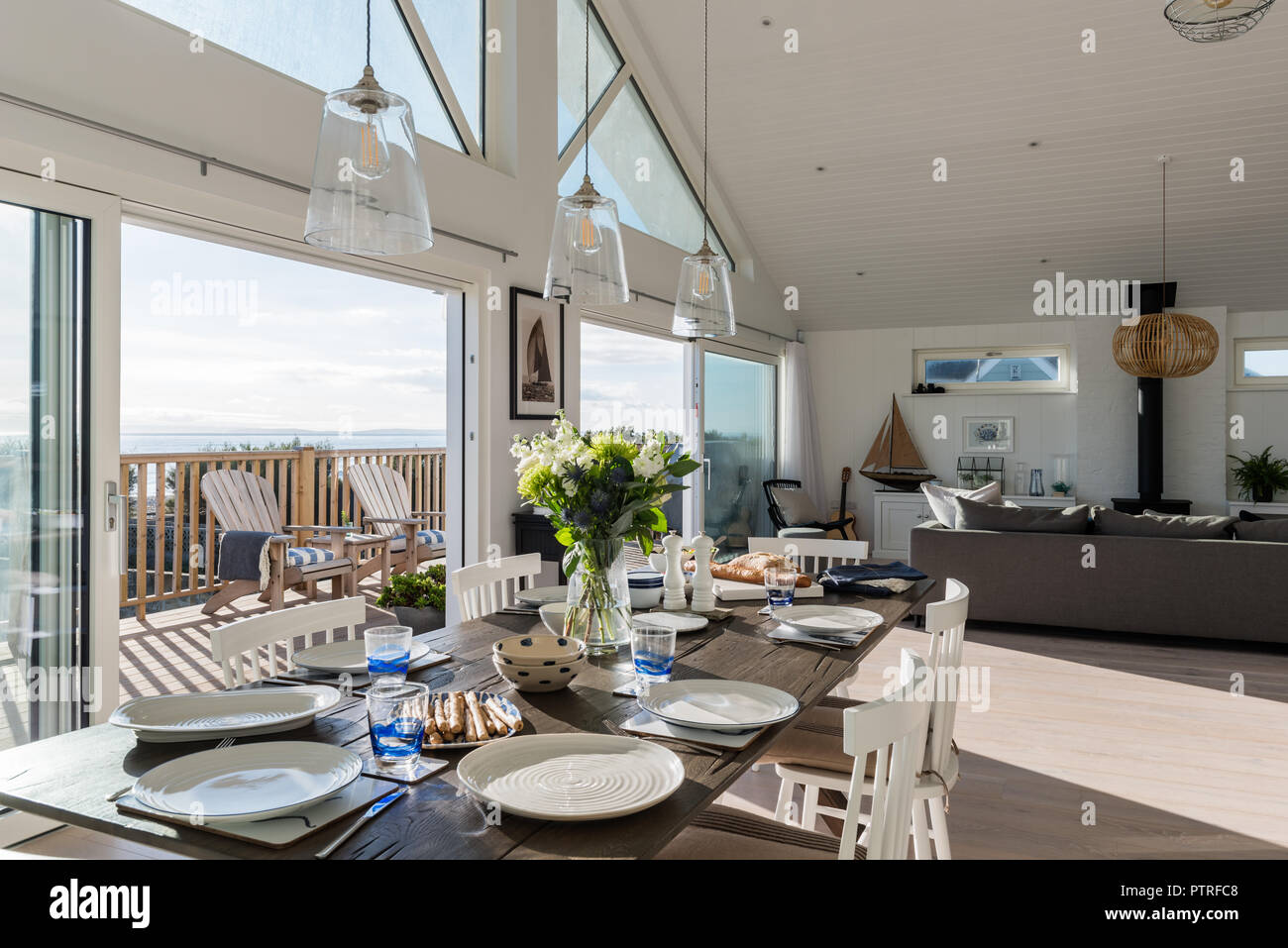 Les fleurs coupées sur la table à manger avec des plaques et voir, par la porte de terrasse en bois Banque D'Images