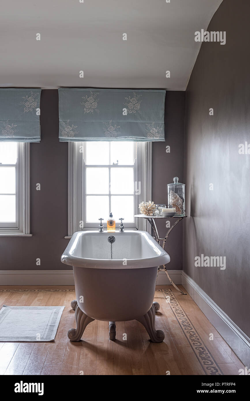 Ferme du 16ème siècle rénovation baignoire sur pieds avec emboidered à rideaux bleu clair dans la fenêtre ferme du xvie siècle restauré Banque D'Images