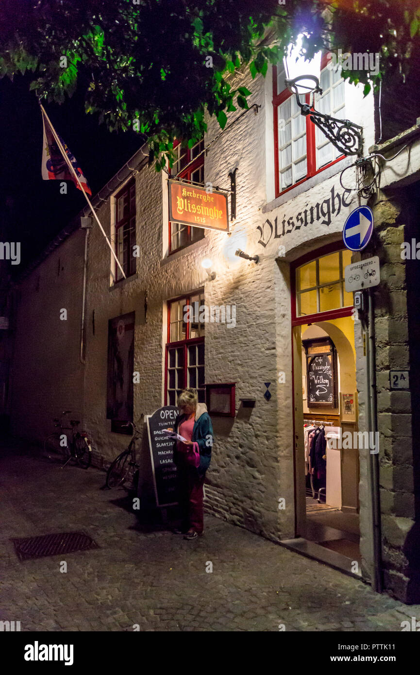 Une femme lisant un site extérieur Café Vlissinghe, de nuit, Bruges, Brugge (Belgique), Banque D'Images