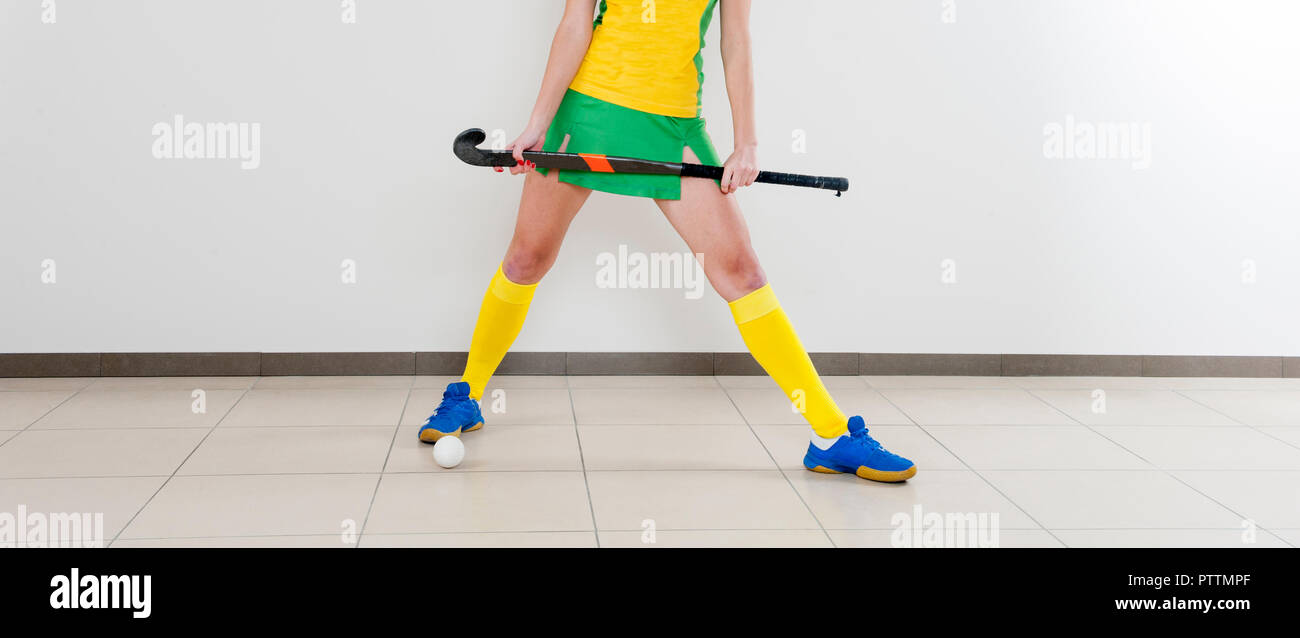 Belle Jeune femme tenant le bâton de hockey et de balle contre fond blanc Banque D'Images