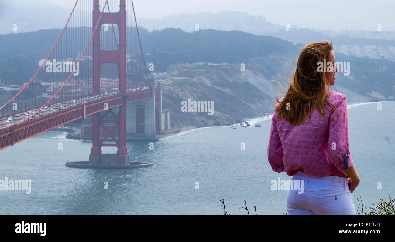 Une femme debout touristique au bord de la falaise au niveau de la batterie Spencer avec le Golden Gate Bridge et San Francisco dans l'arrière-plan avec la San Francisco Banque D'Images