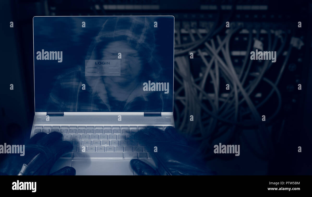 Hacker avec un ordinateur portable sur un fond sombre de câblage structuré. Close-up d'hommes de mains dans des gants noirs sur le clavier, de flou. Tête de l'espion dans le capot. Banque D'Images