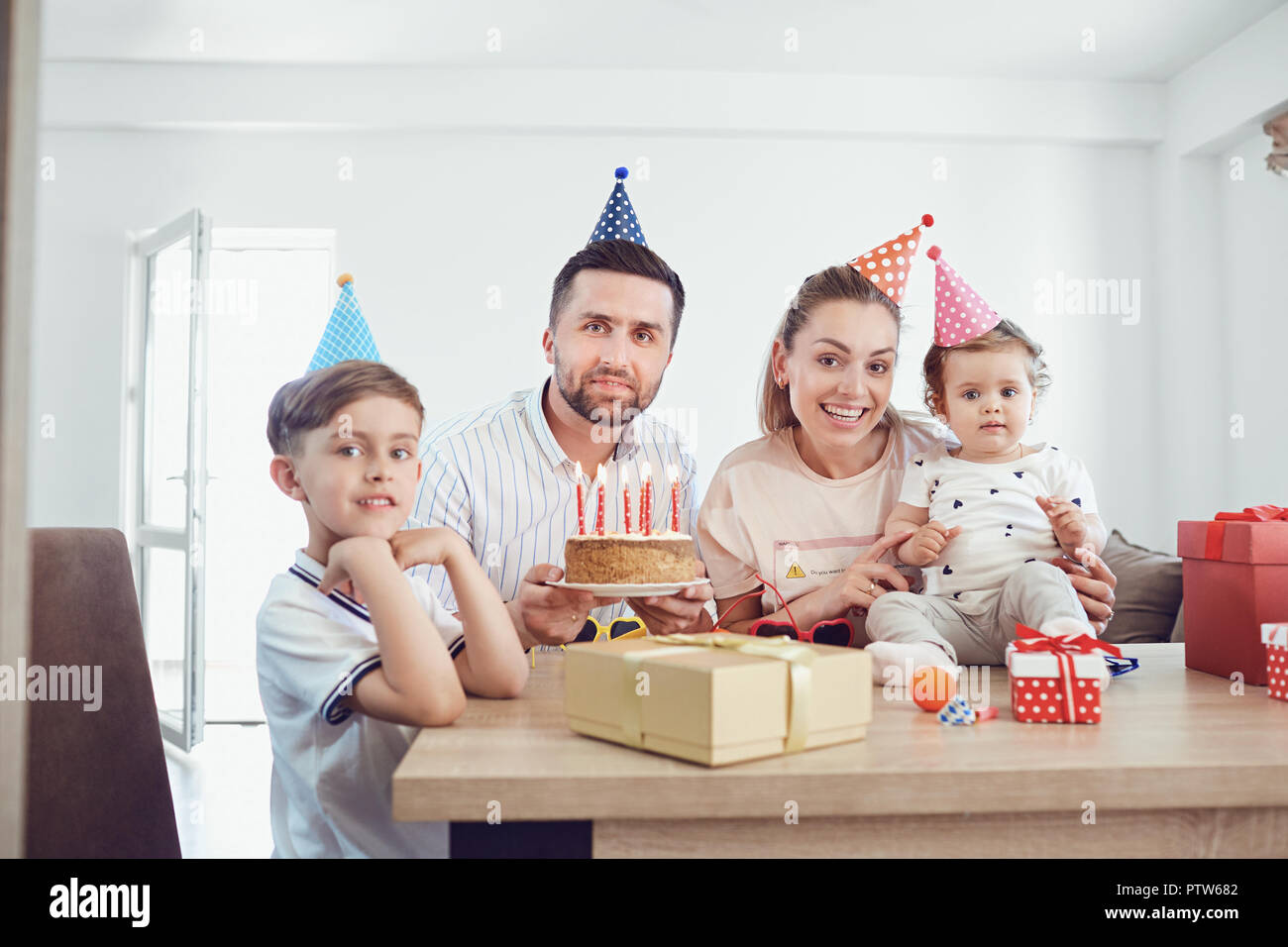 Une famille avec une bougie gâteau célèbre une fête d'anniversaire. Banque D'Images
