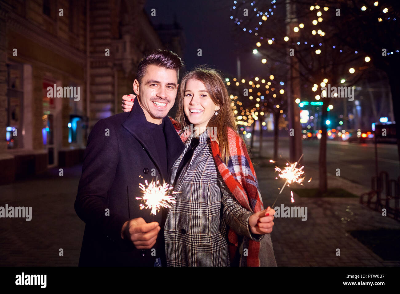 Un jeune couple avec des baguettes dans les mains à Noël. Banque D'Images