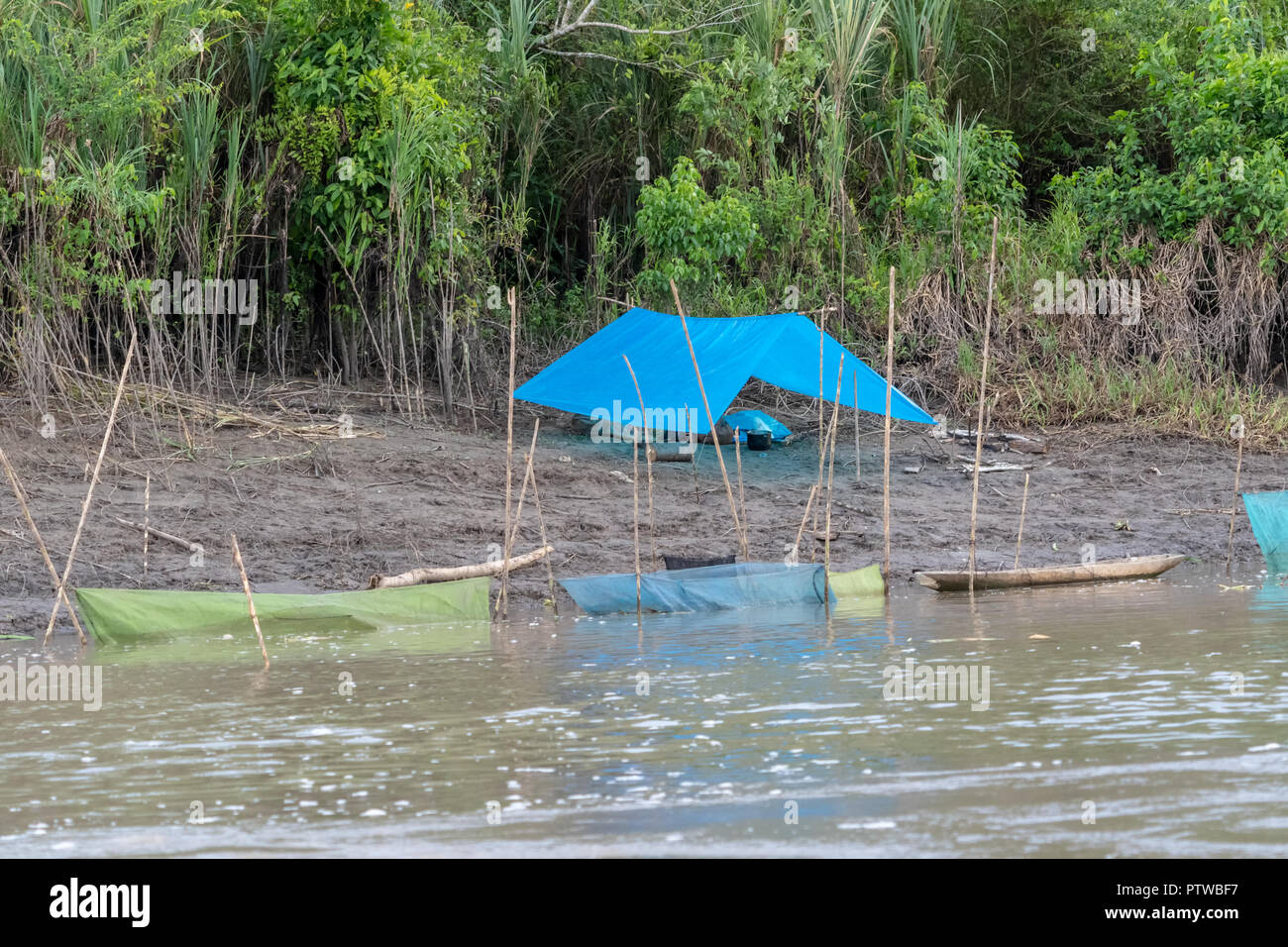 La réserve de Pacaya Samiria, Pérou, Amérique du Sud. Camp de pêche avec une bâche pour une tente, en compagnie de plusieurs enclos pour garder leurs poissons vivants Banque D'Images