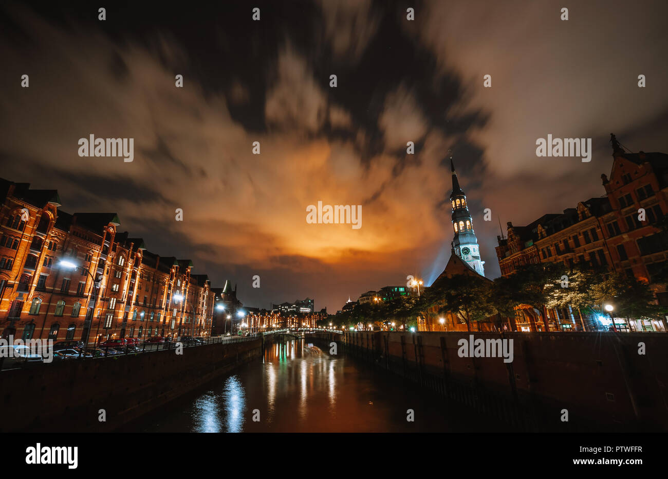 Quartier des entrepôts de Speicherstadt Hamburg de nuit avec vue depuis le pont vers l'église Saint Catherines et Elbphilharmonie. Cityscape at night. La réflexion des lumières sur l'eau et du ciel. Banque D'Images