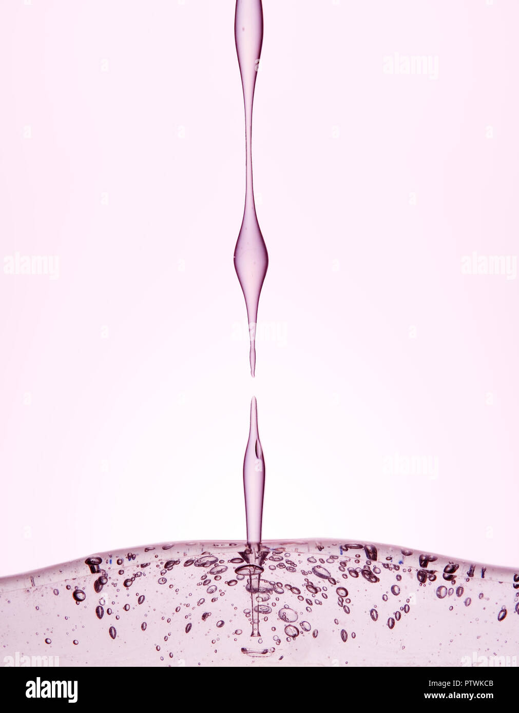 Verser le liquide rose pâle transparente contre fond rose Banque D'Images