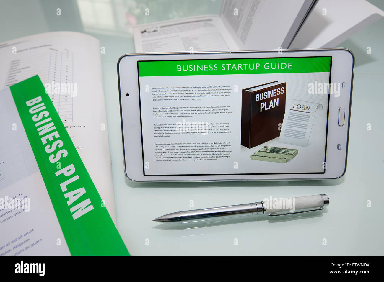 Guide de démarrage d'entreprises sur une tablette ou un téléphone mobile avec des documents plan d'affaires et de fantaisie stylo pour écrire. Banque D'Images