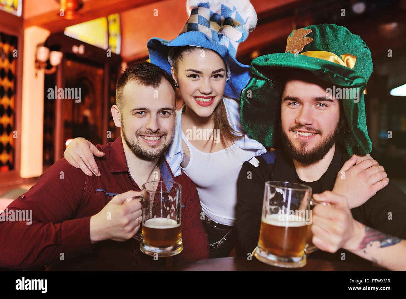 Amis - garçons et filles dans les chapeaux de boire une bière bavaroise sur l'arrière de la zone au cours de la célébration de la fête de la bière ou le jour de la Saint Patrick Banque D'Images