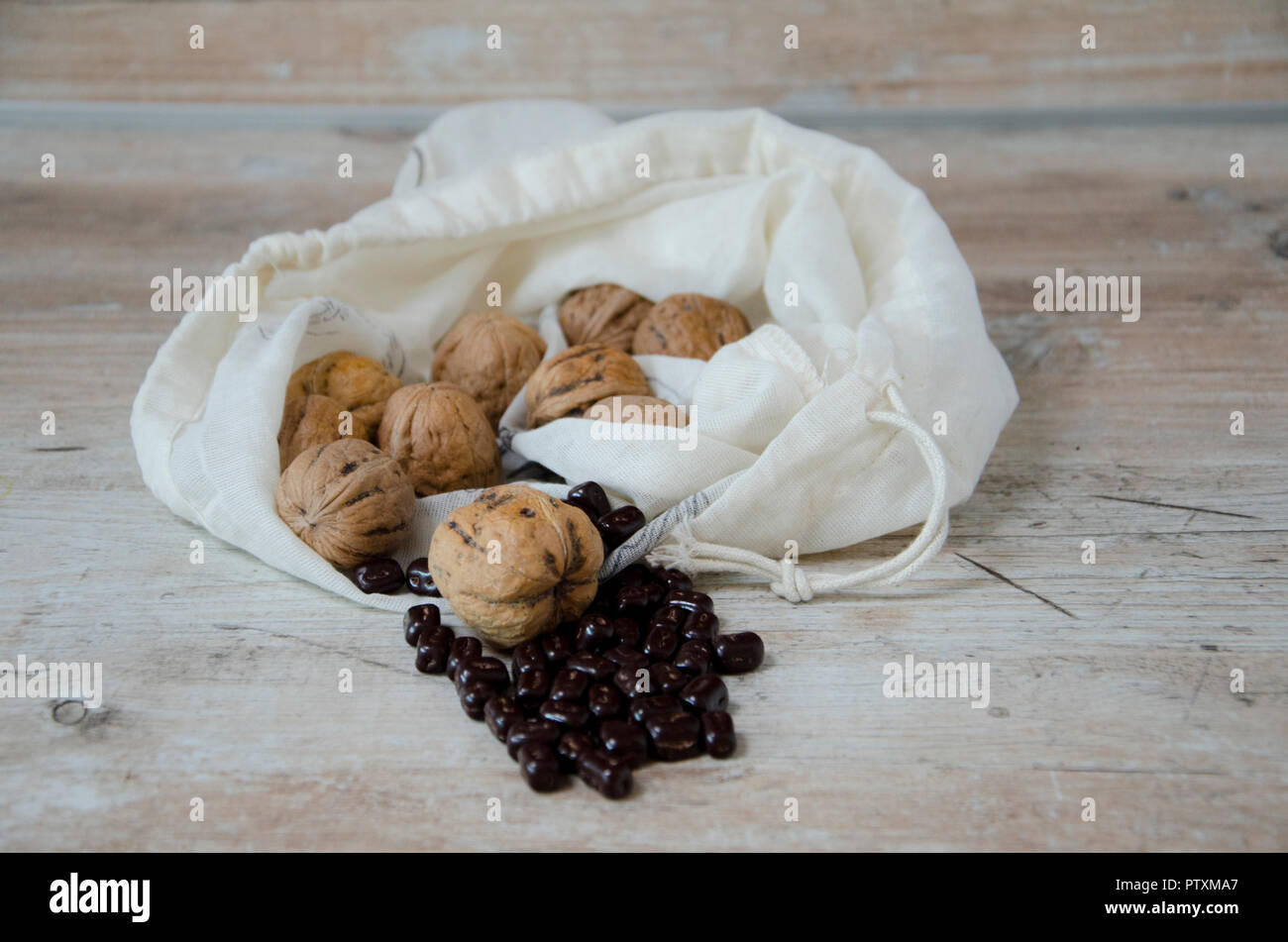 Les noix dans un sac de billes de chocolat sur une table de cuisine en bois Banque D'Images