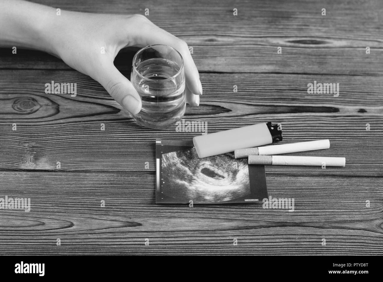 A woman's hand est titulaire d'un verre d'alcool, à côté c'est une photo de l'uzi la grossesse et les cigarettes, la grossesse et le tabagisme, la cigarette Banque D'Images