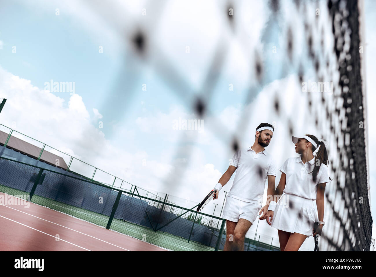 Ils jouent comme une équipe. Belle jeune femme et l'homme holding tennis racket et discuter ensemble Banque D'Images