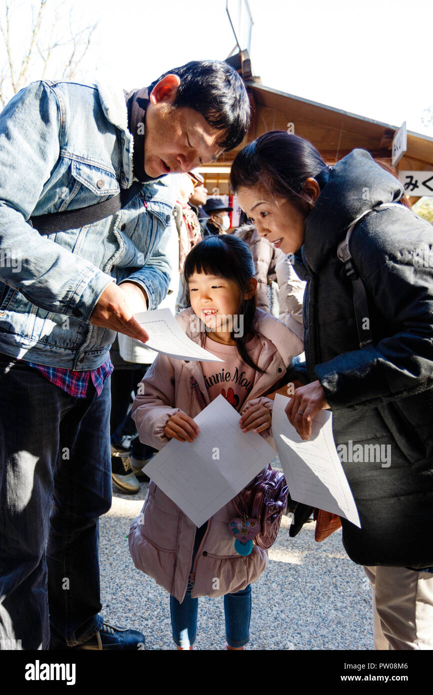 Nouvel An japonais, shogatsu. Les parents, se pencher pour lire fortune glisser de Omikuji papier pour leur fille, fille, 4-5 ans. Nishinomiya culte. Banque D'Images