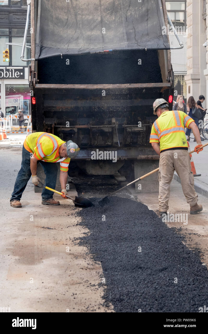 La réfection de deux travailleurs de la construction d'une route qui avait été ouvert pour réparer les tuyaux à vapeur, sur Waverly Place à Greenwich Village, New York City. Banque D'Images