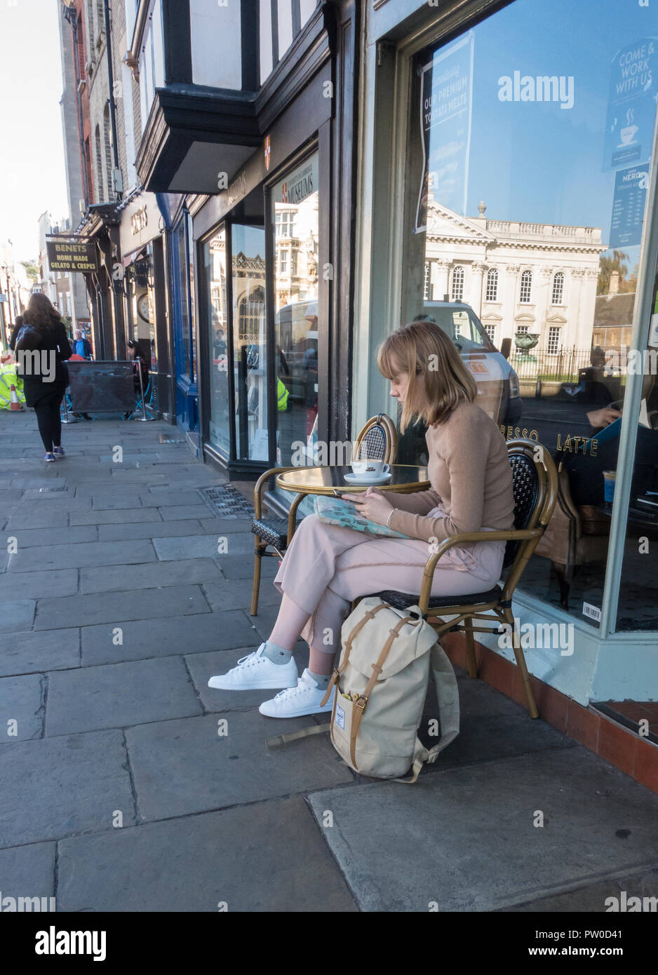 Jeune femme se reposant à l'extérieur du café à l'aide de mobile phone Banque D'Images