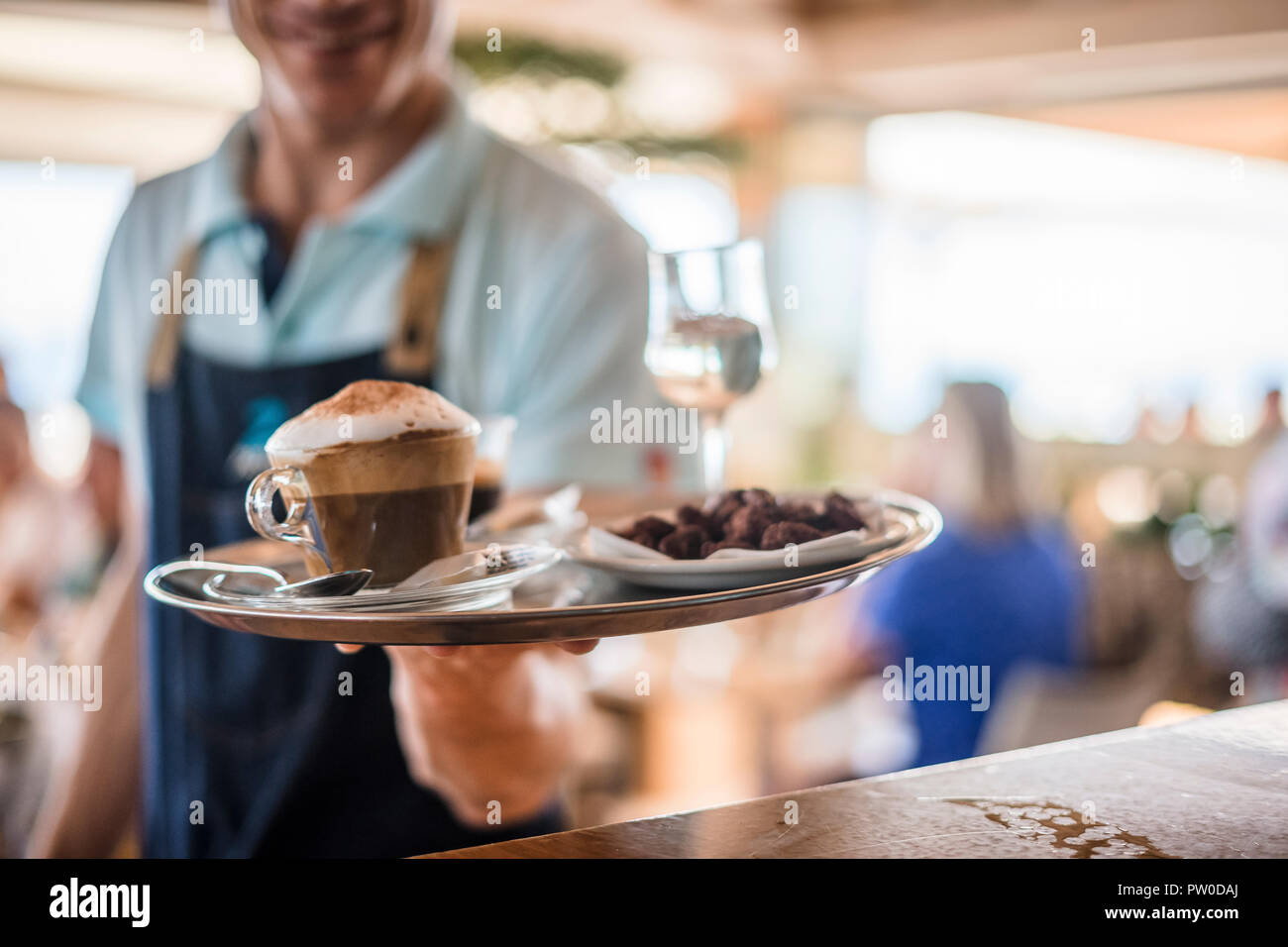 Garçon porte bac avec du cappuccino, un verre de vin et desser Banque D'Images