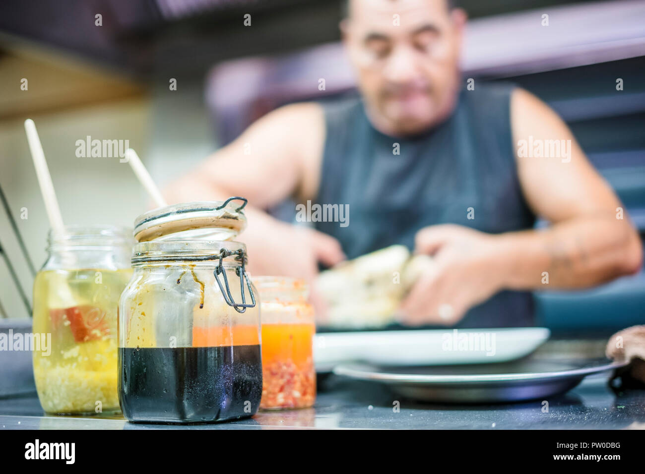 L'homme préparer un poisson pour barbecue avec les sauces épicées colorés en premier plan Banque D'Images