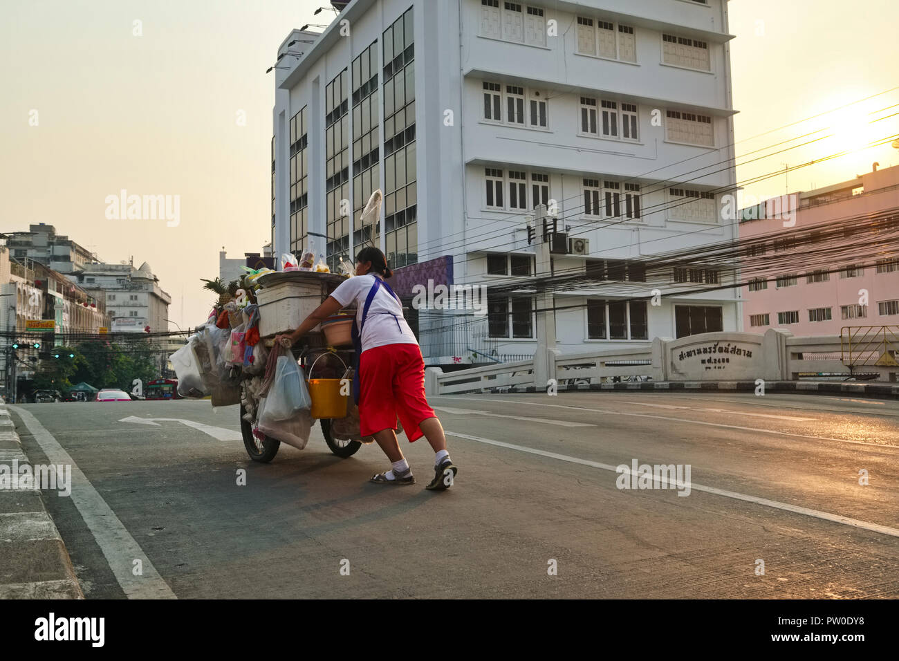 Un fournisseur d'aliments à Bangkok, Thaïlande, en poussant son chariot sur un klong (canal) bridge de mettre en place sa soirée food Banque D'Images