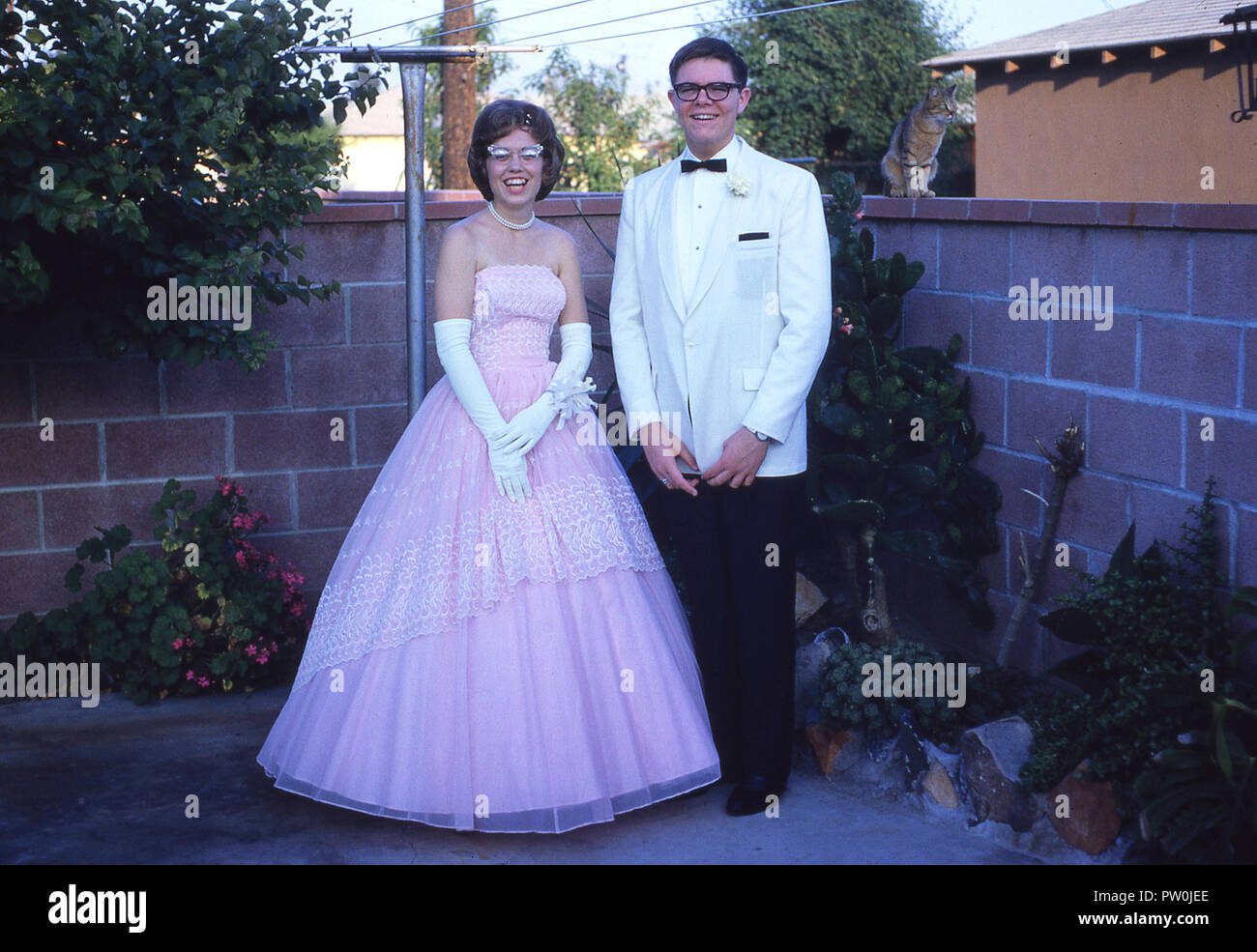 1962, l'Amérique, aller au bal.....un jeune homme vêtu d'un smoking blanc et et une jeune femme portant une longue robe rose à froufrous se tenir ensemble pour une photo avant d'assister au bal, un traditionnel important et fin de la danse à long terme et l'événement pour nous les élèves du secondaire. Dans les années 50 et 60, le bal était plus d'un couple, l'événement, où un garçon lui demande une fille d'être sa date et serait son escorte après avoir sélectionné son jusqu'à son domicile et avoir beaucoup de photo prises ! Banque D'Images