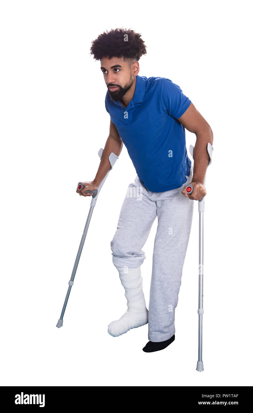 Homme avec jambe cassée à l'aide de béquilles sur fond blanc Banque D'Images