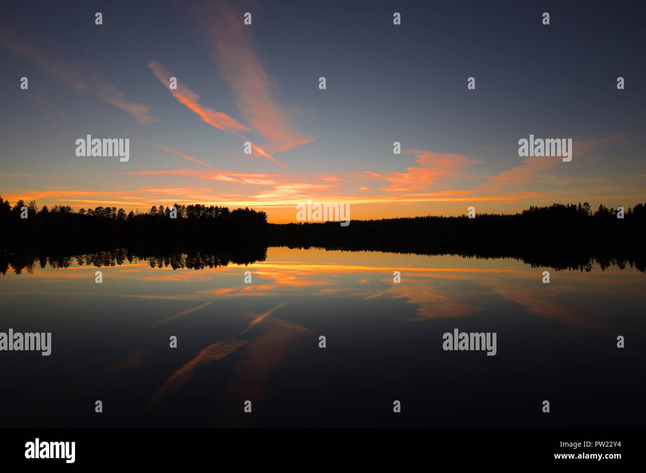 Belle et colorée de l'automne coucher de soleil sur un lac entouré de forêts dans la région de Dalarna, Suède. Banque D'Images