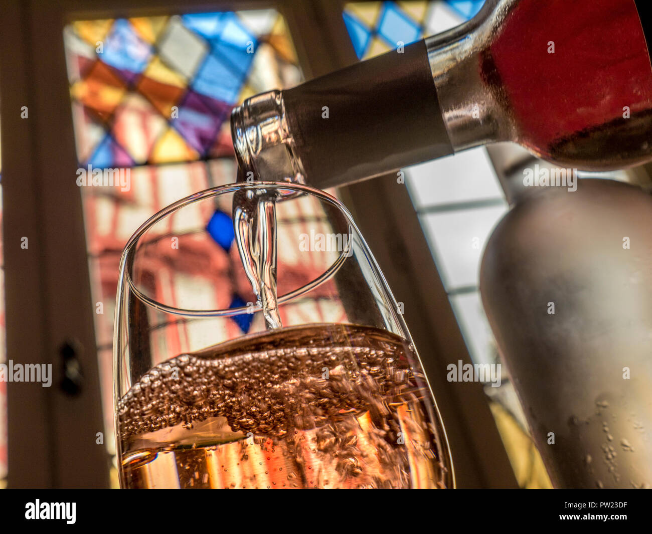 Rosé restaurant verre versant bar à vin situation table, avec vitraux colorés et la vieille ville de vannes derrière la Bretagne Finistère France Banque D'Images