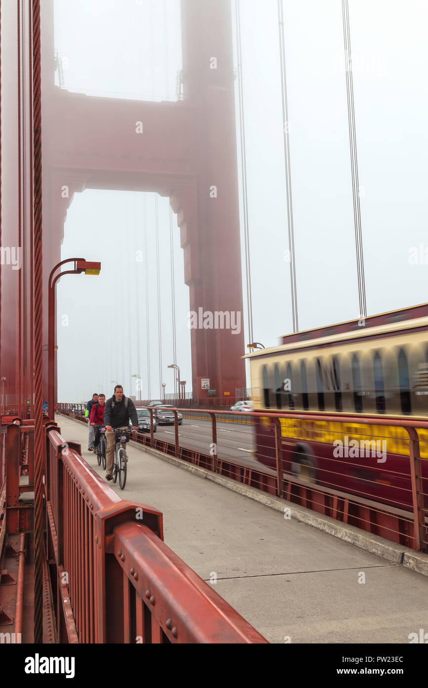 Vététistes et un autobus d'excursion sur le Golden Gate Bridge San Francisco, California, United States, sur un fin brouillard matin d'été. Banque D'Images