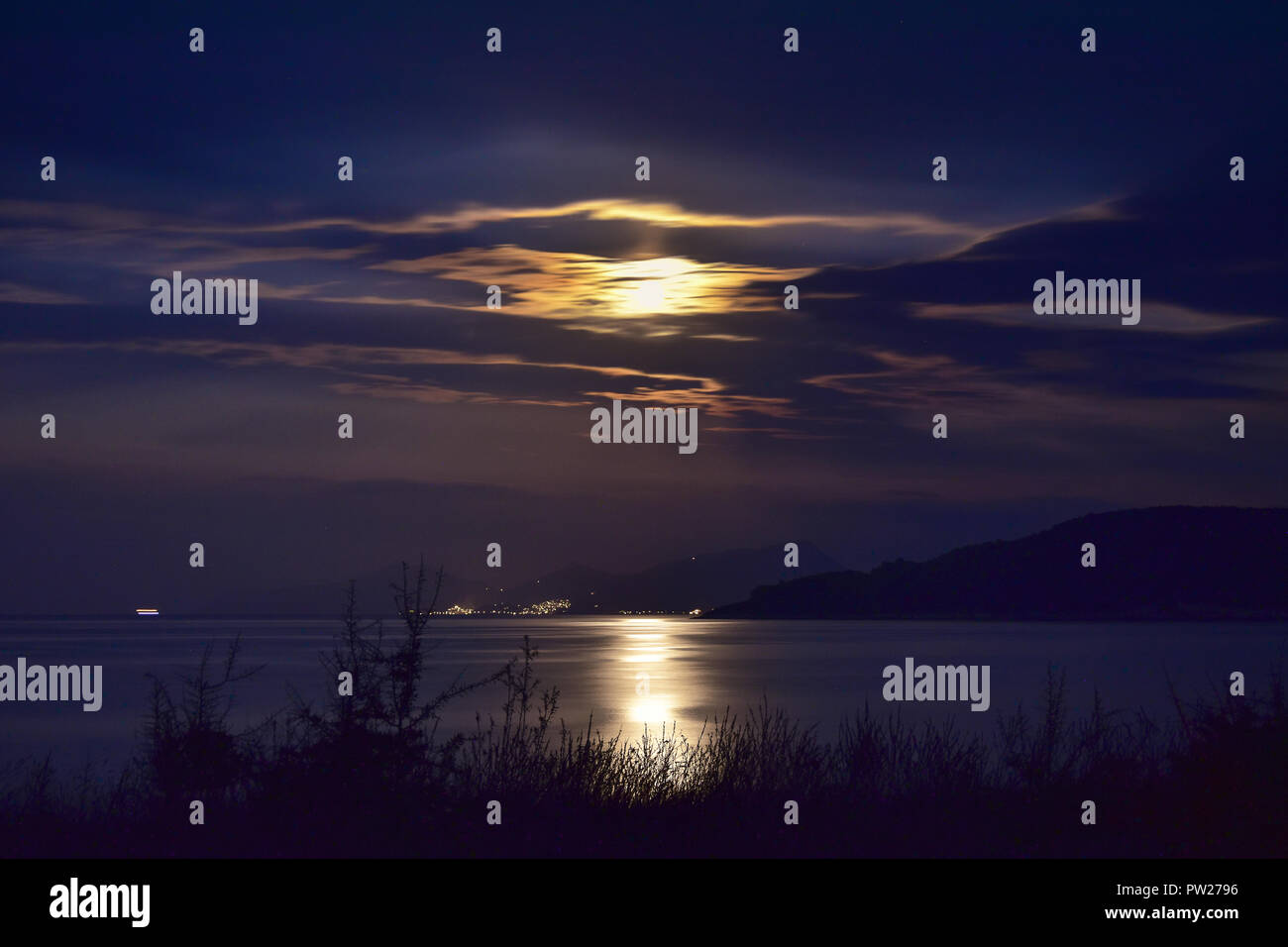 Superbe lumière de lune à travers les nuages spectaculaires de la mer et de la réflexion. Banque D'Images