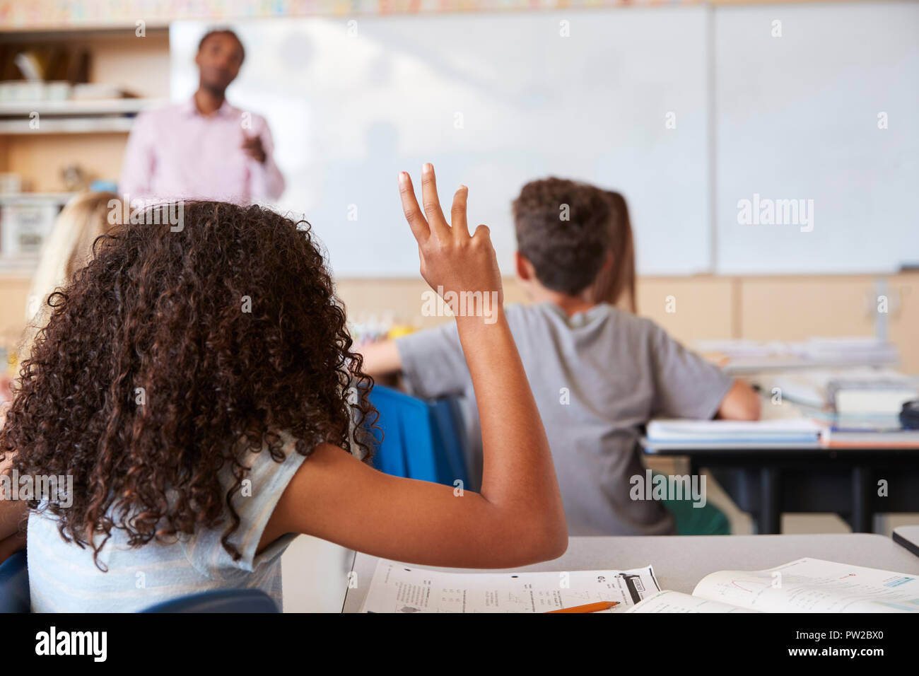 Girl raising hand de répondre dans une classe de l'école élémentaire Banque D'Images