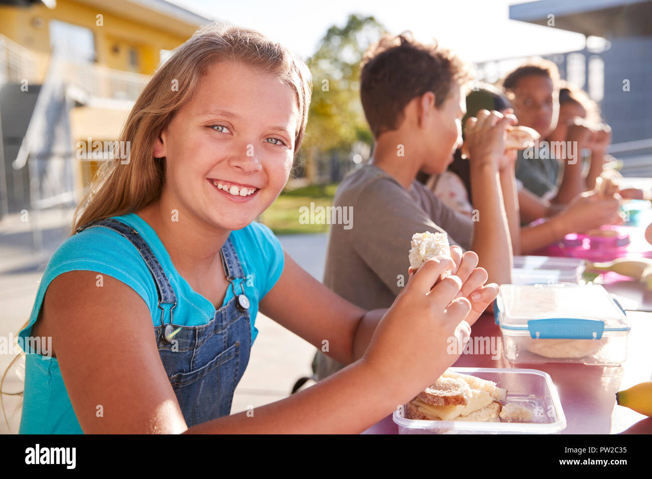 Fille à l'école élémentaire le déjeuner table à l'appareil photo Banque D'Images