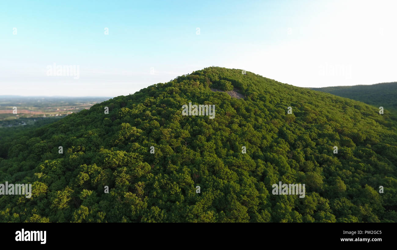 Seule la montagne verte avec des arbres et un ciel clair. Vous pouvez voir la vallée en arrière-plan. Certaines roches sont poussant dehors au dessus. Banque D'Images