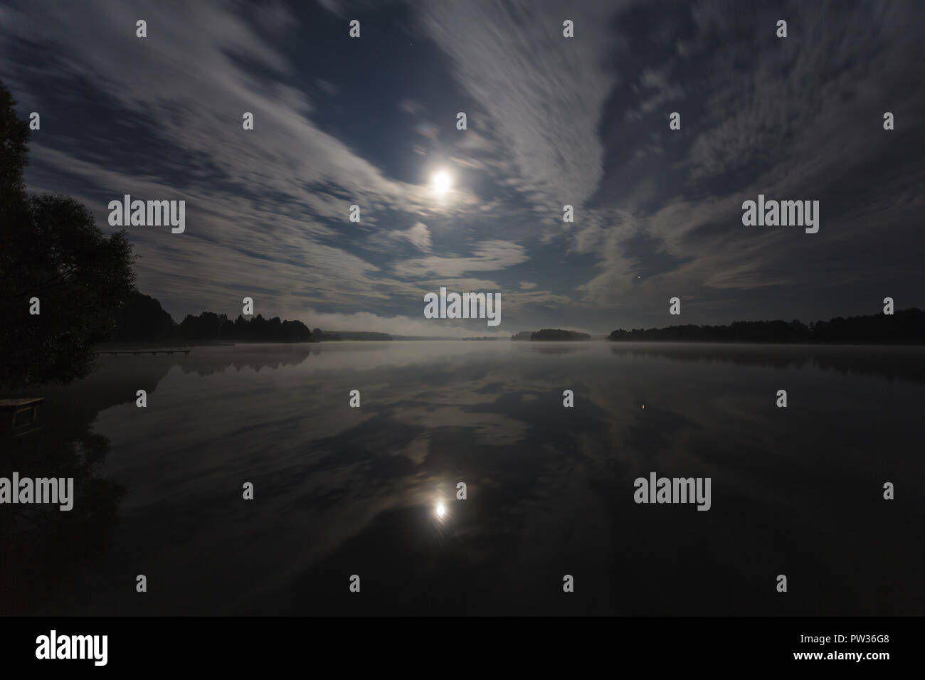 Nuages dans la nuit sur le lac éclairé par la pleine lune, d'une exposition longue shot Banque D'Images