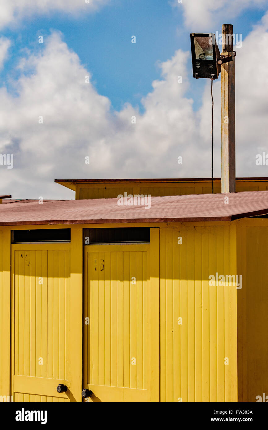 Belles maisons de bain jaune sur la plage de sable. Abris vides sur une journée ensoleillée mais Moody. Architecture balnéaire, peinture colorée, labyrinthe de labyrint. Banque D'Images