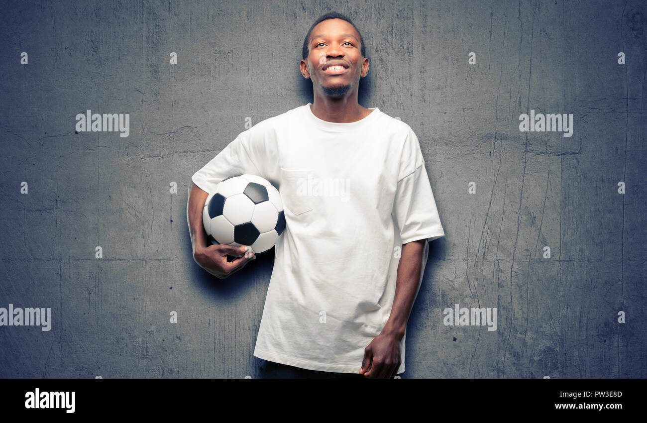 African black man holding soccer ball penser et à exprimer le doute et me demande de Banque D'Images